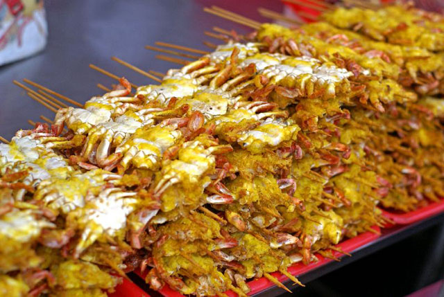 Small dried crab kebabs are piled up on trays. 