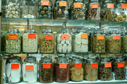 Étalage de produits divers d'origine organique placés dans des pots de verre étiquetés et alignés sur trois rangées.