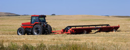 A side view of a tractor mowing in a field crop. 