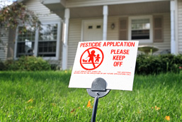 Small sign standing on a lawn informing of the spraying of pesticides. 