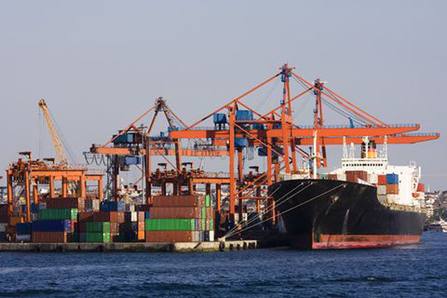 Vue panoramique d'activités portuaires: conteneurs, grues, et bateau amarré.