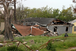 Construction humaine démolie et clôture endommagée suite au passage d'un ouragan.